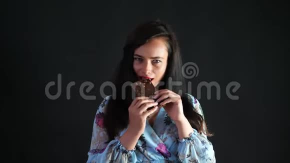 一位红唇黑发女人的肖像她爱色且玩味地吃黑巧克力和榛子和视频的预览图