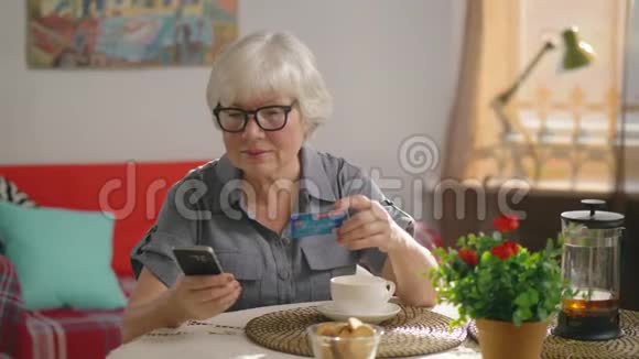 祖母坐在她舒适的客厅里的一张桌子旁买东西视频的预览图