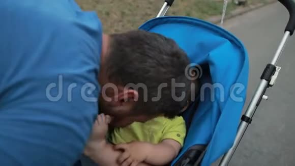 可爱的父亲在婴儿车里和蹒跚学步的儿子玩耍视频的预览图
