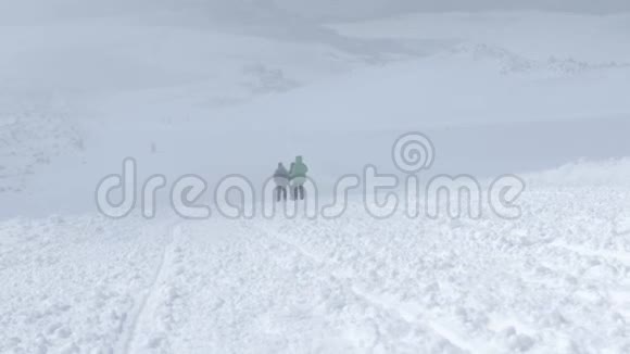 一家人一个十几岁的孩子爸爸妈妈在雪地里从一座山峰上下来脚上戴着特殊的猫福格可怜视频的预览图