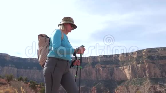 肥胖的成熟女人带着徒步旅行杆和背包在大峡谷徒步旅行视频的预览图