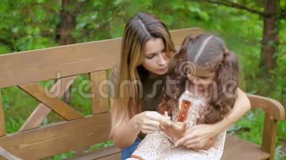 妈妈坐在长凳上她腿上有个小女孩女人带着孩子玩无忧无虑的笑开心的坐在上面视频的预览图