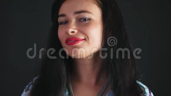 一位红唇黑发女人的肖像她爱色且玩味地吃黑巧克力和榛子和视频的预览图
