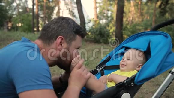 可爱的父亲在公园亲吻他的小儿子的脚视频的预览图