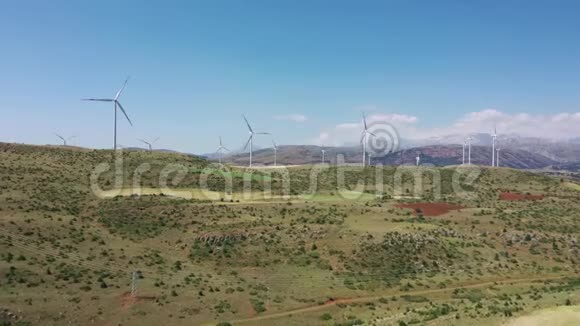 风力涡轮机和农场拖拉机在田野上色雷斯风力涡轮机底部附近的拖拉机碾磨尘土飞扬的田地视频的预览图