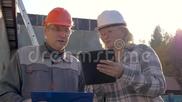 建筑工人和建筑师在头盔中讨论按计划施工视频的预览图