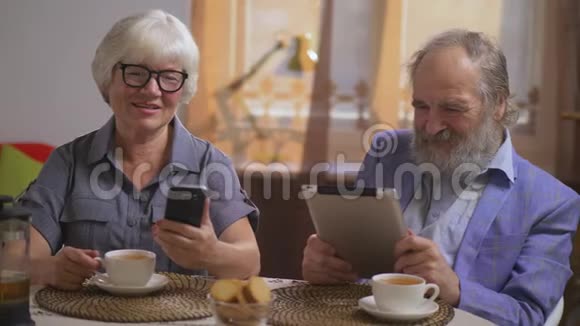 一对老夫妇坐在餐桌旁端着小玩意在餐厅里喝茶视频的预览图