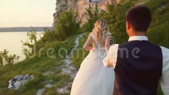 恋爱中的情侣在海滨的海滨石头间散步慢动作视频的预览图