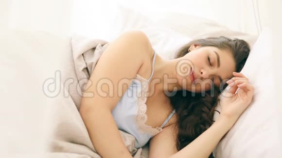 年轻漂亮的女人睡在舒适的床单上录像片段视频的预览图