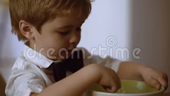 男孩吃粥小孩一边吃粥一边看动画片儿童独立概念视频的预览图