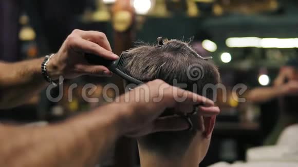 慢镜头理发师用剪刀和梳头的手的特写镜头视频的预览图