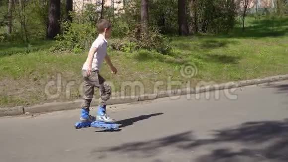 可爱的男孩骑在公园里的溜冰鞋上视频的预览图