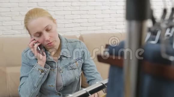 坐在沙发上的女人打电话检查挂在衣架上的一套牛仔裤视频的预览图