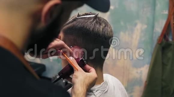 胡子理发师用电动修剪器在一个人的耳朵后面一条直线年轻英俊的白种人视频的预览图