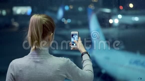 现代机场航站楼玻璃墙旁站着一个英俊的女孩为飞机拍照视频的预览图