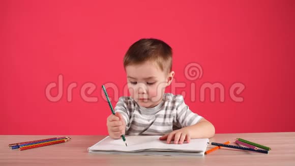 快乐的孩子用铅笔在相册里画画孤立在粉红色上视频的预览图
