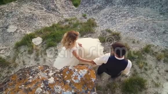 恋爱中的情侣在海滨的海滨石头间散步慢动作视频的预览图