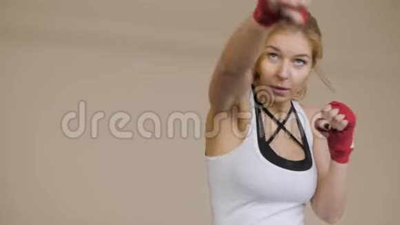 年轻女子用手裹着红色的拳击磁带拳击漂亮的女拳击手在健身房训练视频的预览图