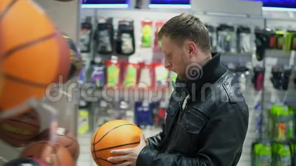 一个穿黑色皮夹克的成年男子选择一个篮球进行户外运动视频的预览图
