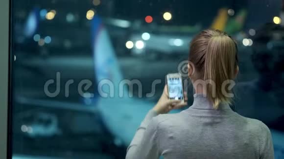 现代机场航站楼玻璃墙旁站着一个英俊的女孩为飞机拍照视频的预览图