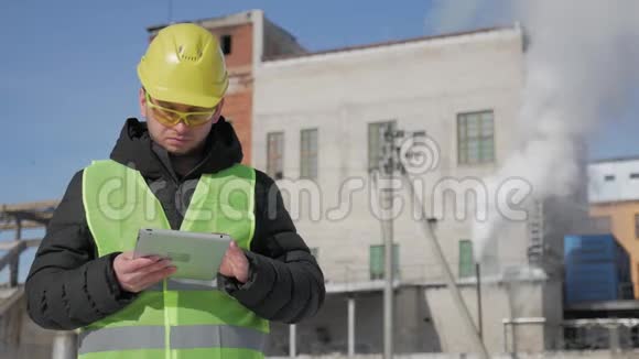 戴安全帽的工程师正在一家工业工厂使用平板电脑视频的预览图