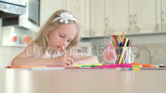 一个可爱的小女孩坐在桌子上用铅笔画画视频的预览图