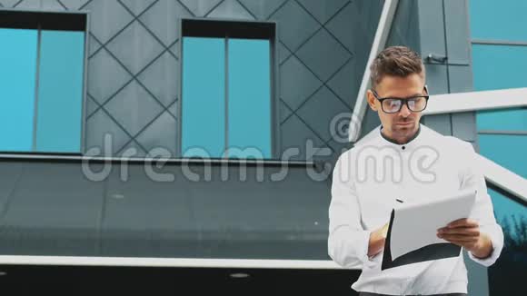一个年轻的商人站在办公室手里拿着一个文件夹视频的预览图