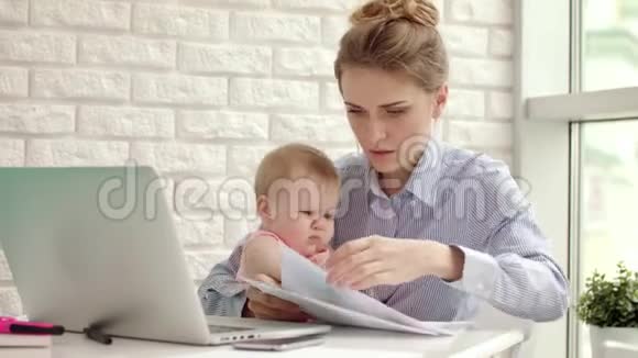 做生意的母亲和孩子在家工作母亲带着孩子看文件视频的预览图