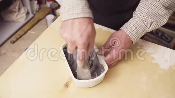 老人的手在一个小塑料盒子里搅拌水泥视频的预览图