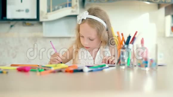 一个可爱的小女孩坐在桌子上用铅笔画画视频的预览图