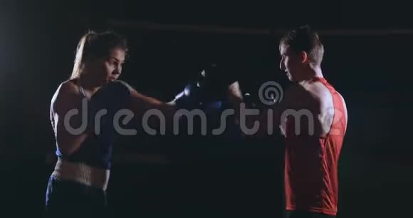 女拳击手在烟雾弥漫的健身房里用拳击手套打聚焦拳视频的预览图