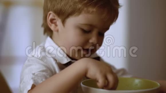 小孩一边吃粥一边看动画片儿童独立概念男孩吃粥视频的预览图