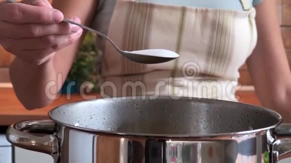 女人在沸水中放盐和意大利面慢动作视频视频的预览图