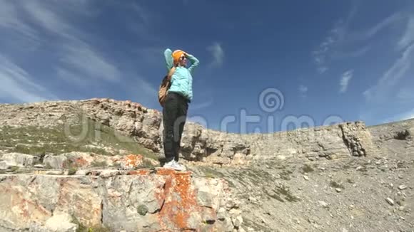一个背着背包的女孩走在靠近悬崖的高原上旅行概念视频的预览图