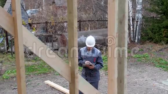 房子前面的白人工人建筑师或建筑商检查半建木框架房屋的计划一个建筑商视频的预览图