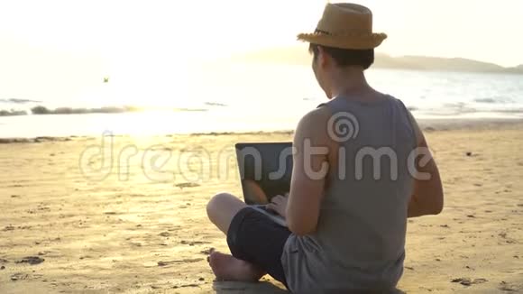 匿名的自由职业者在海边使用笔记本电脑视频的预览图