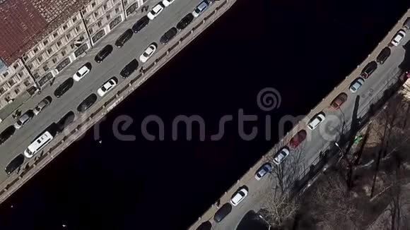 俯视道路停放的汽车和沿着河道行走的人停在水渠的空中视频的预览图
