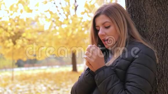 冻僵的女人站在秋天的街道上树温暖了她的双手呼吸视频的预览图