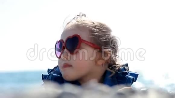 小女孩在海边的海滩上在一个风和日丽的日子里戴着一副心形眼镜爱的概念视频的预览图