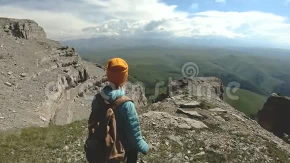 一个背着背包的女孩走在靠近悬崖的高原上旅行概念视频的预览图