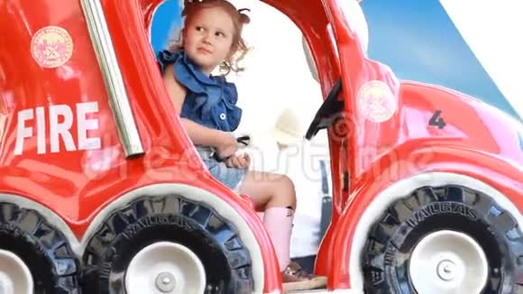 小女孩在公园里骑着消防车娱乐儿童景点视频的预览图