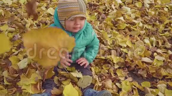 快乐微笑的小男孩在公园里玩落叶慢动作视频的预览图