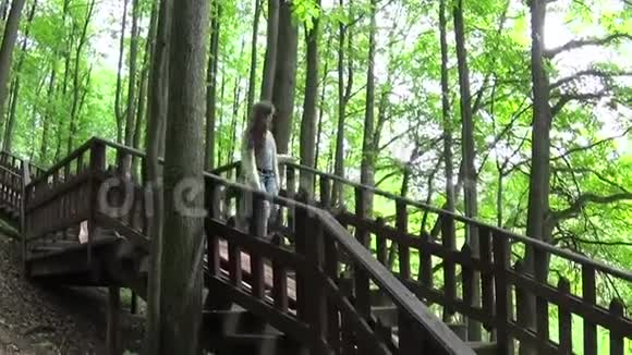 可爱的少女走下公园的木制楼梯视频的预览图