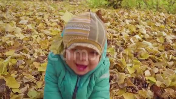 快乐微笑的小男孩在公园里玩落叶慢动作视频的预览图
