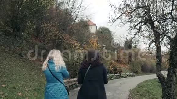 秋天的秋天两个年轻的女人在公园散步友谊观视频的预览图
