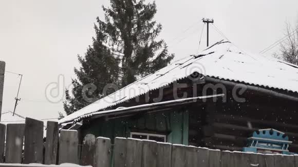 村子里下雪了篱笆后面的旧木房子视频的预览图