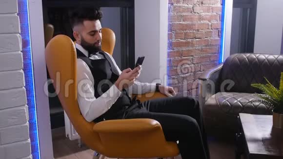 坐在椅子上拿着智能手机的年轻人视频的预览图