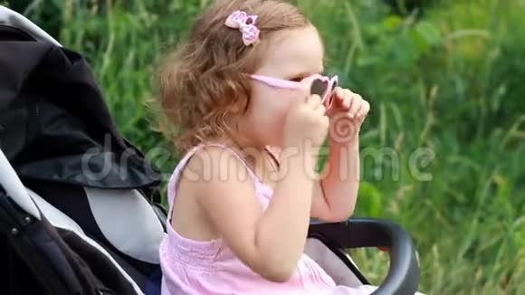 戴着太阳镜的快乐女婴坐在婴儿车里高兴极了视频的预览图