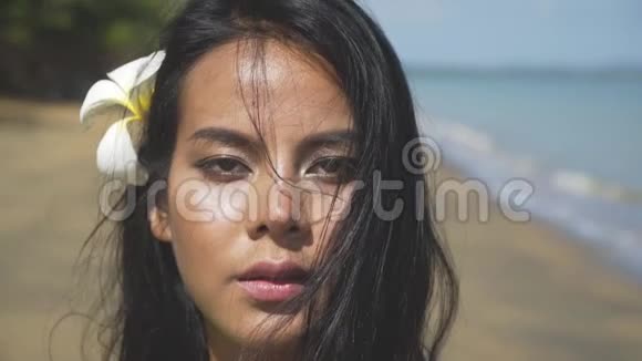 一个美丽的亚洲女孩沿着海滩散步的脸的特写视频的预览图