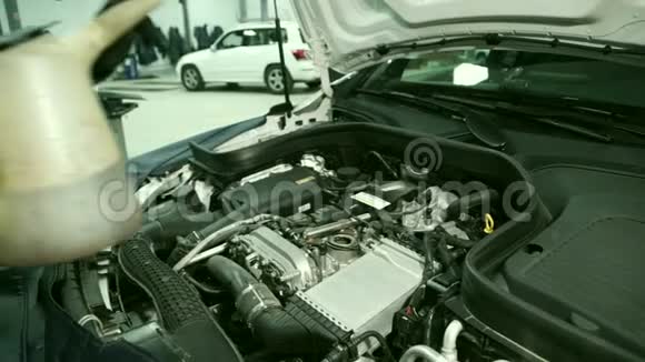 车间的机械师在汽车的引擎盖下给发动机加油视频的预览图